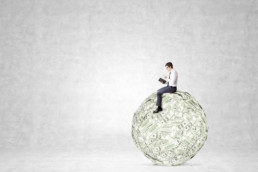 Man sitting on large ball of money